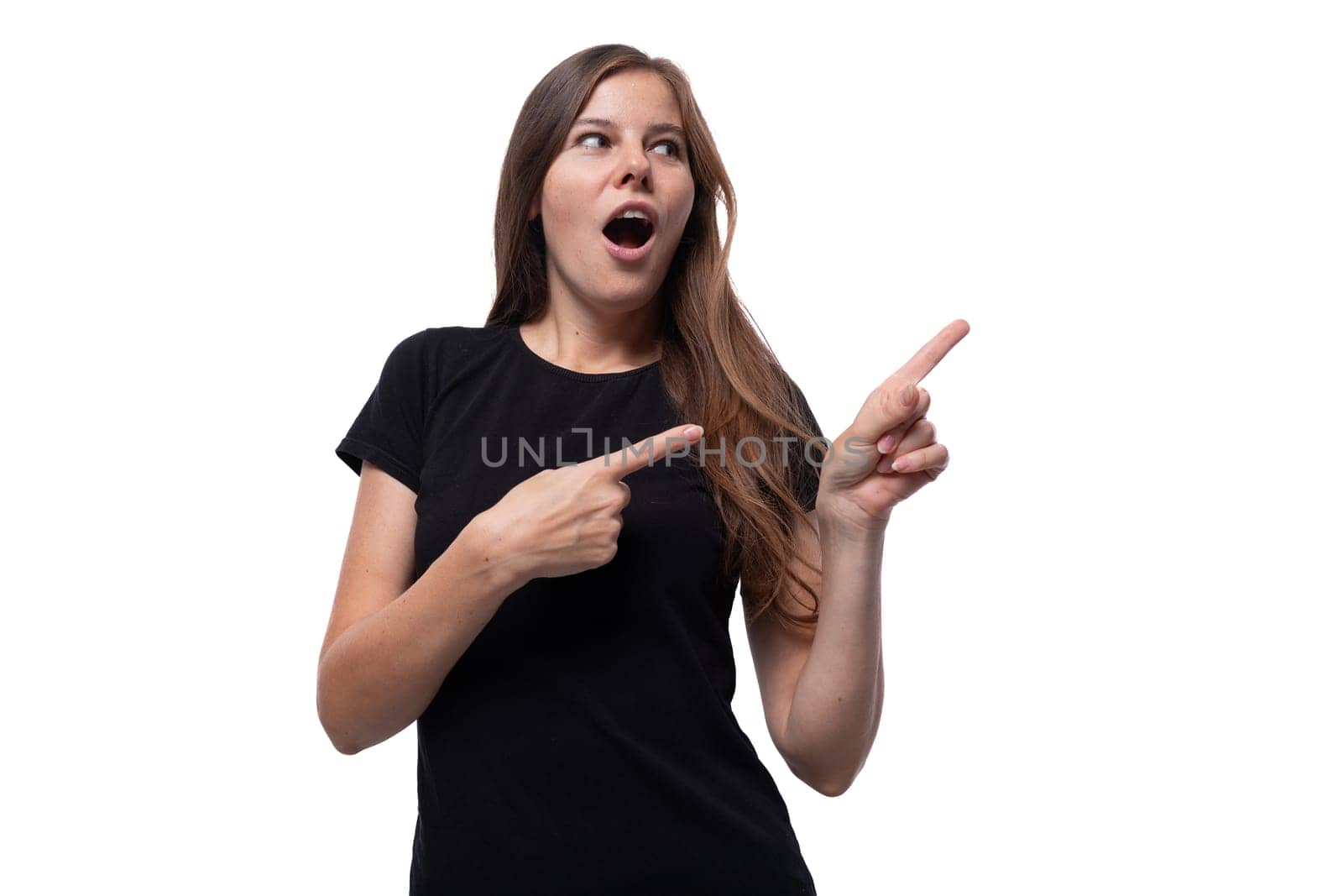 A young woman dressed in a black T-shirt reports interesting news and points her hands to the sides.