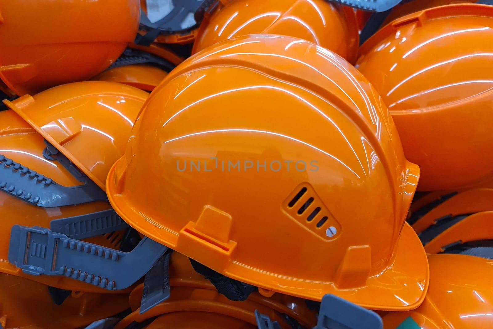 An orange work helmet lies among other similar helmets of general workers.. Construction safety worker equipment.