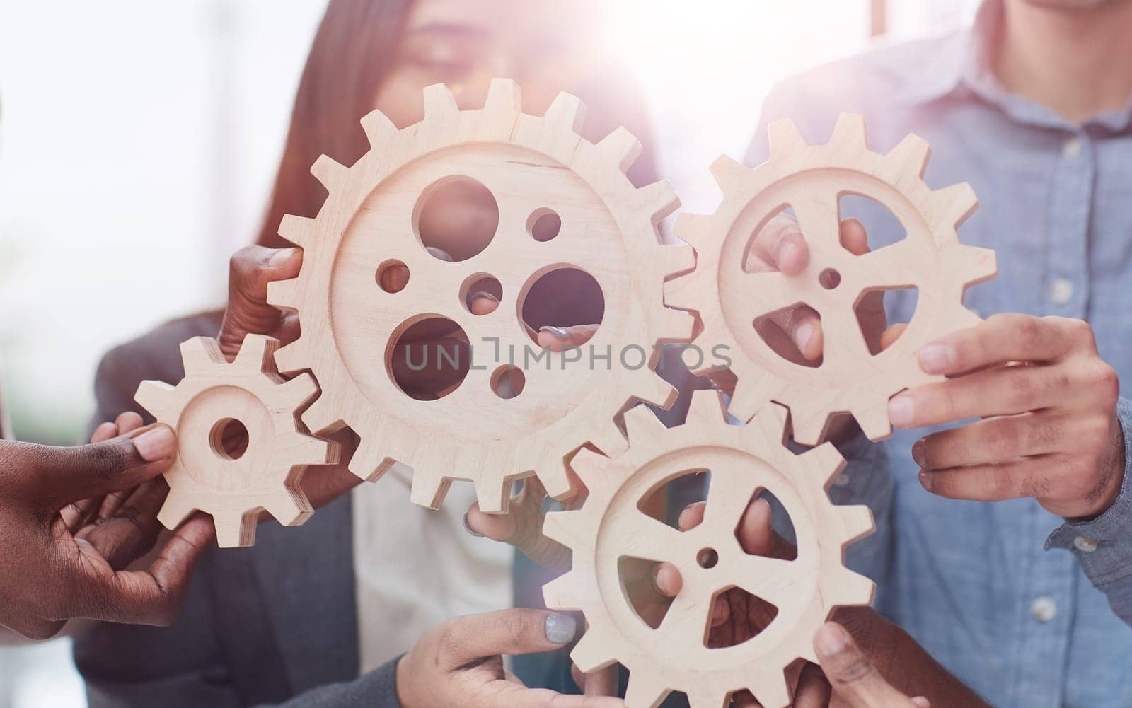 Office worker holding cog wheel as unity and teamwork in corporate workplace concept. by Prosto
