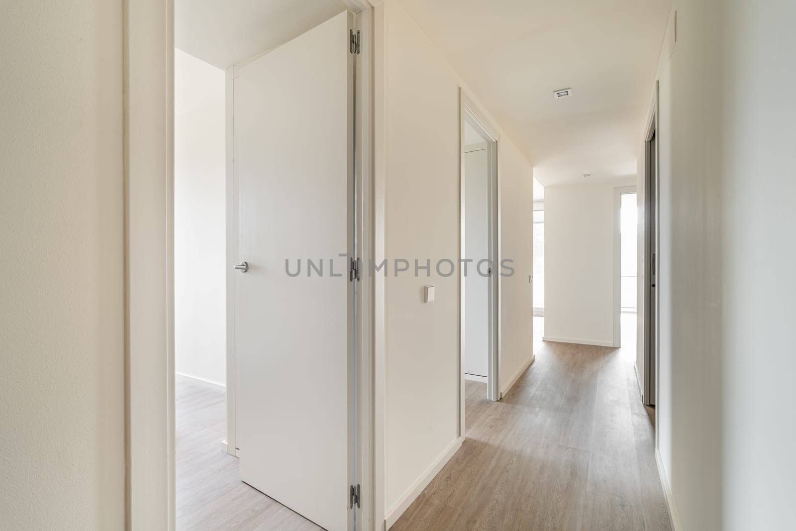Stylish empty long corridor with open doors to different rooms. Bright multi-room designer apartment after renovation without furniture