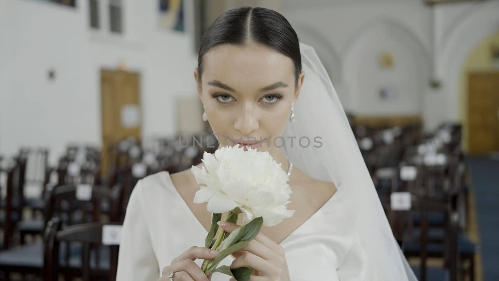 A beautiful bride. Action.Photographing in the registry office where they shoot a pretty girl with big eyes in a wedding white dress with a veil. by Mediawhalestock