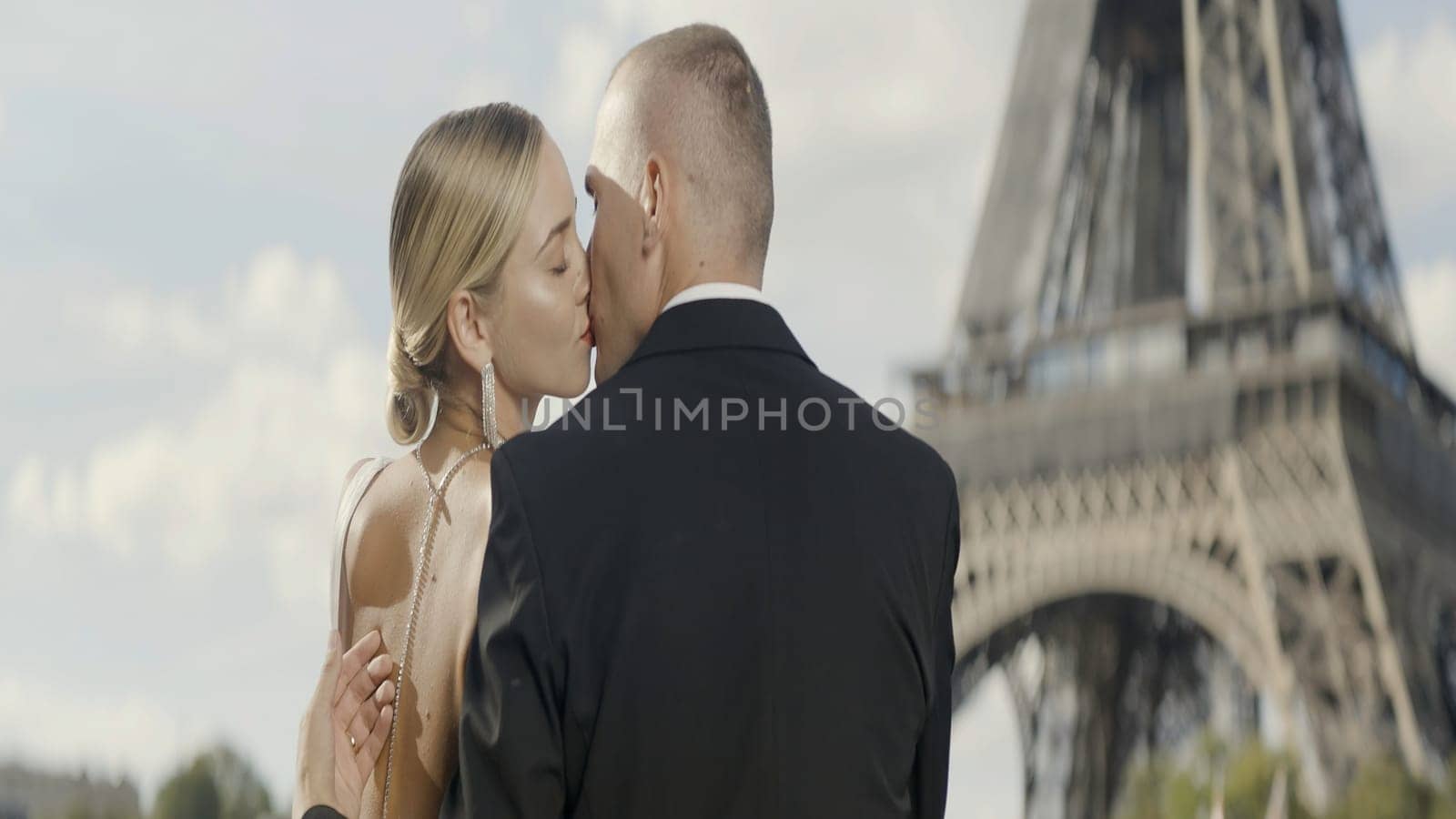 Happy couple having a good time in Paris at the Eiffel Tower. Action. Happy loving man and woman kissing near famous french tower