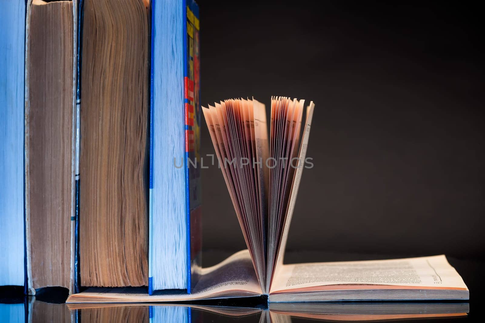 open book for reading and a stack of books, isolated on a black background.