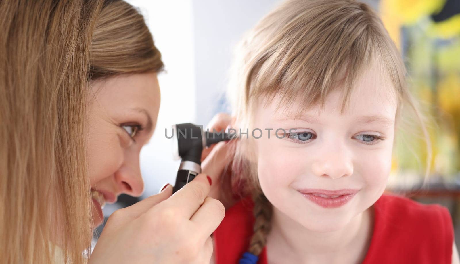 Otorhinolaryngologist looking at sore ear of little girl by kuprevich