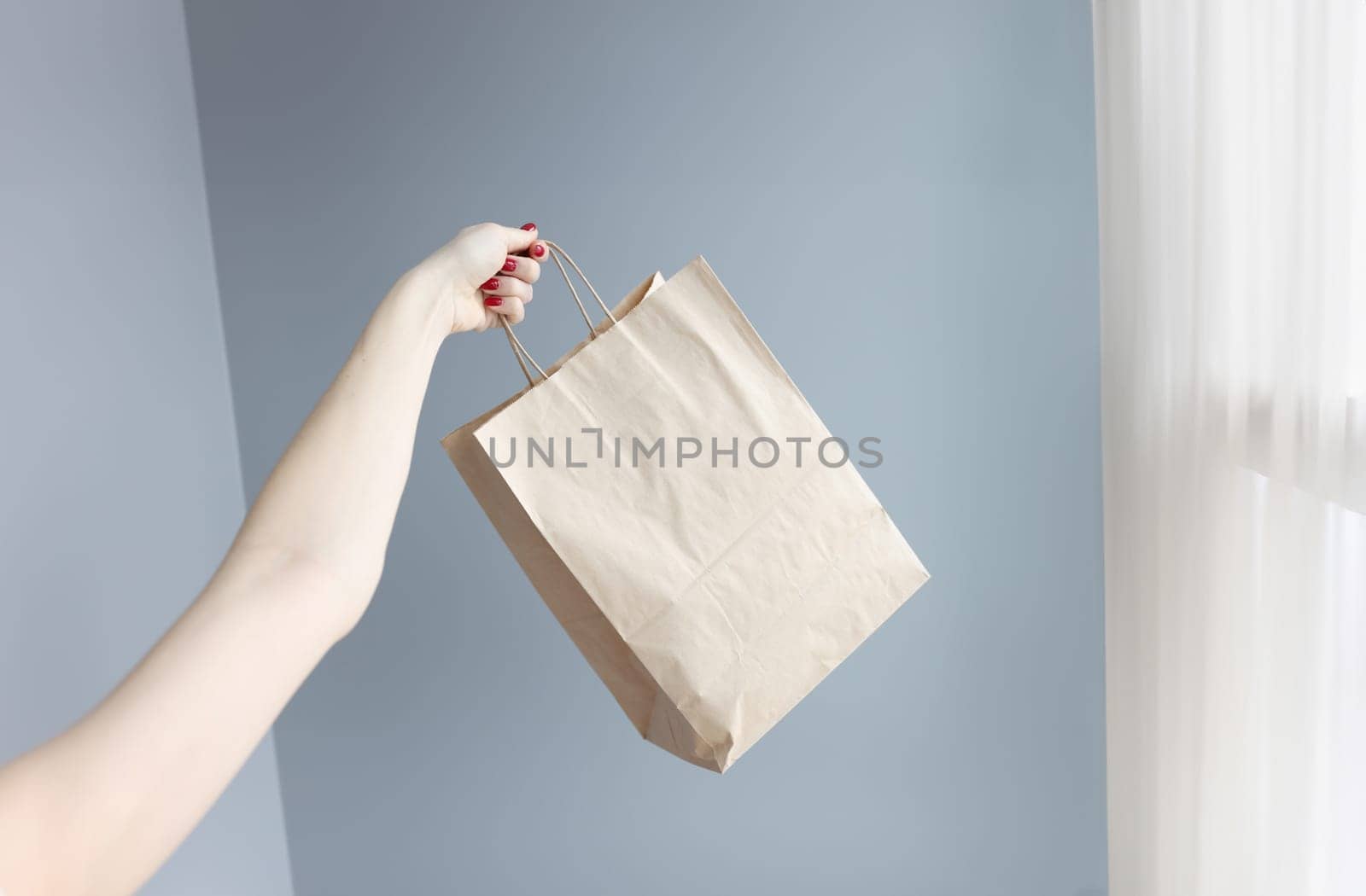 Womans hand holding paper shopping bag closeup. Refusal from plastic packaging concept