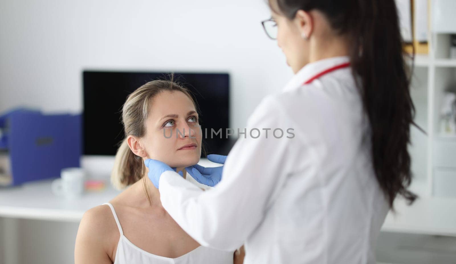 Doctor examining patients submandibular lymph nodes in clinic by kuprevich