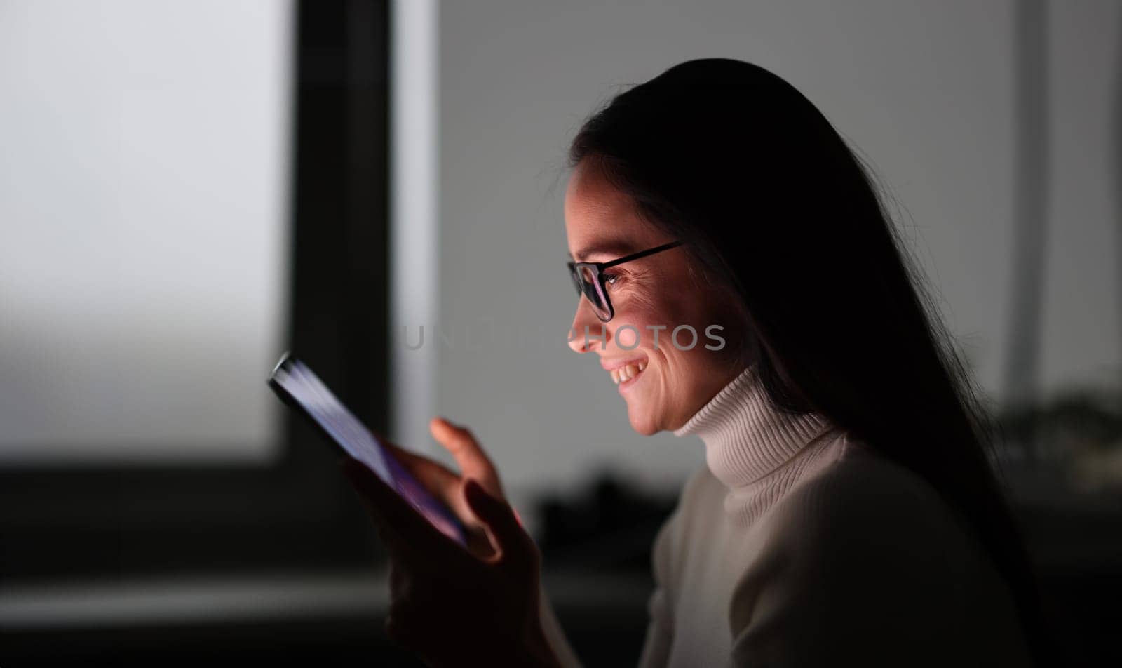 Young woman holding mobile phone at night. Communication in social media concept