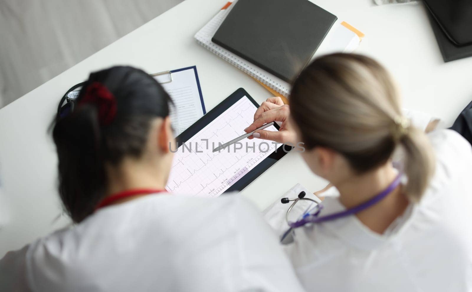 Doctors studying electrocardiogram on digital tablet closeup by kuprevich