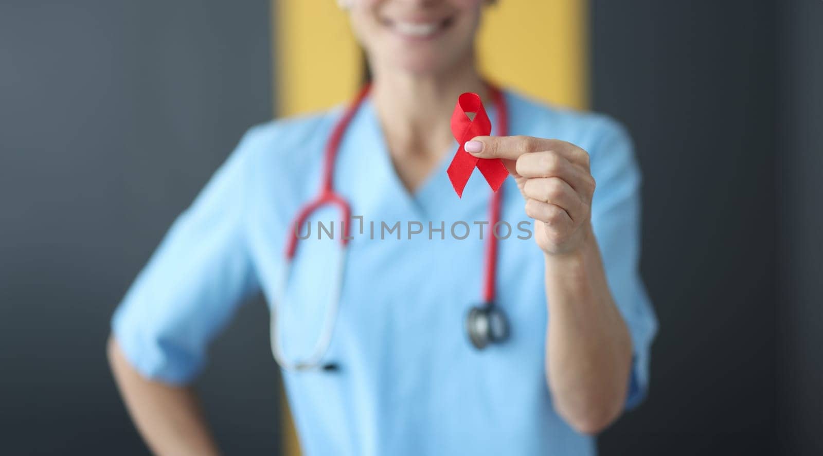 Doctor holding red ribbon in his hands closeup. Aids day concept