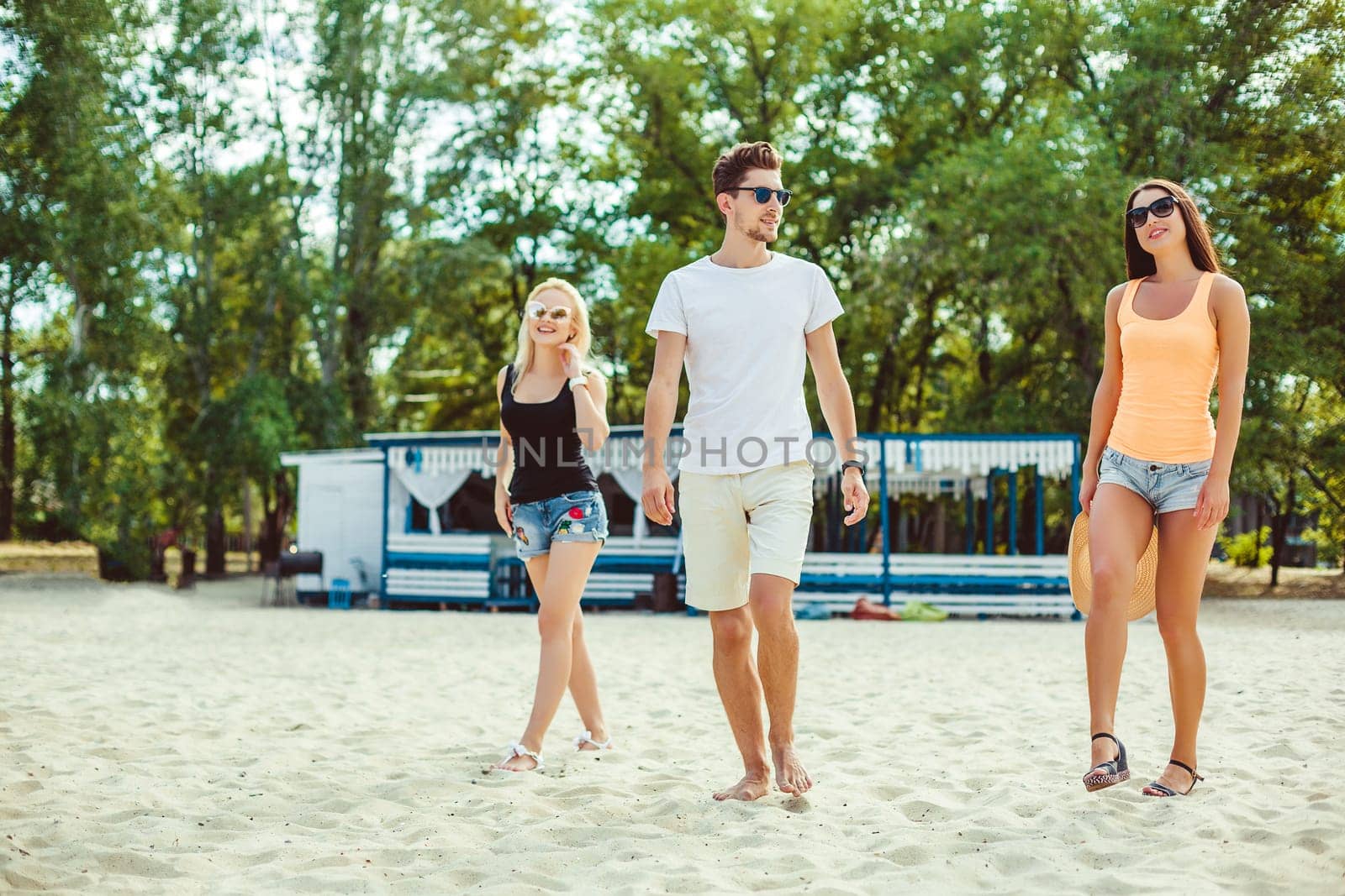 Young funny guys in sunglasses on the beach. Friends together. Summer bar is on background.