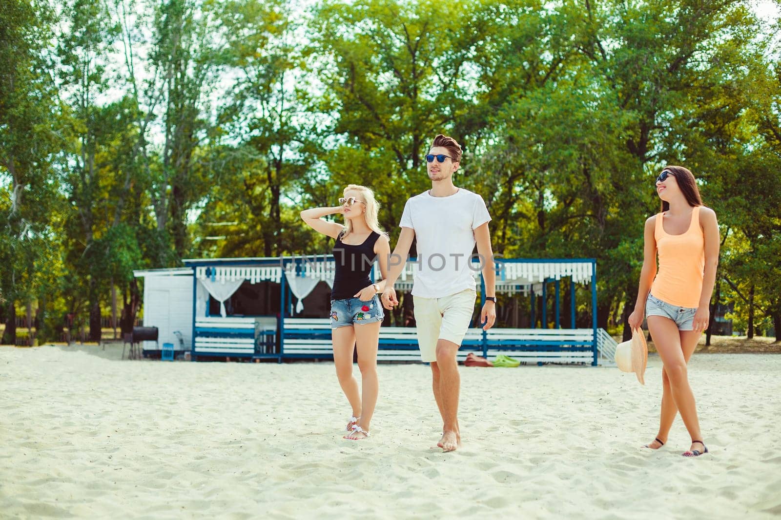 Young funny guys in sunglasses on the beach. Friends together. Summer bar is on background.