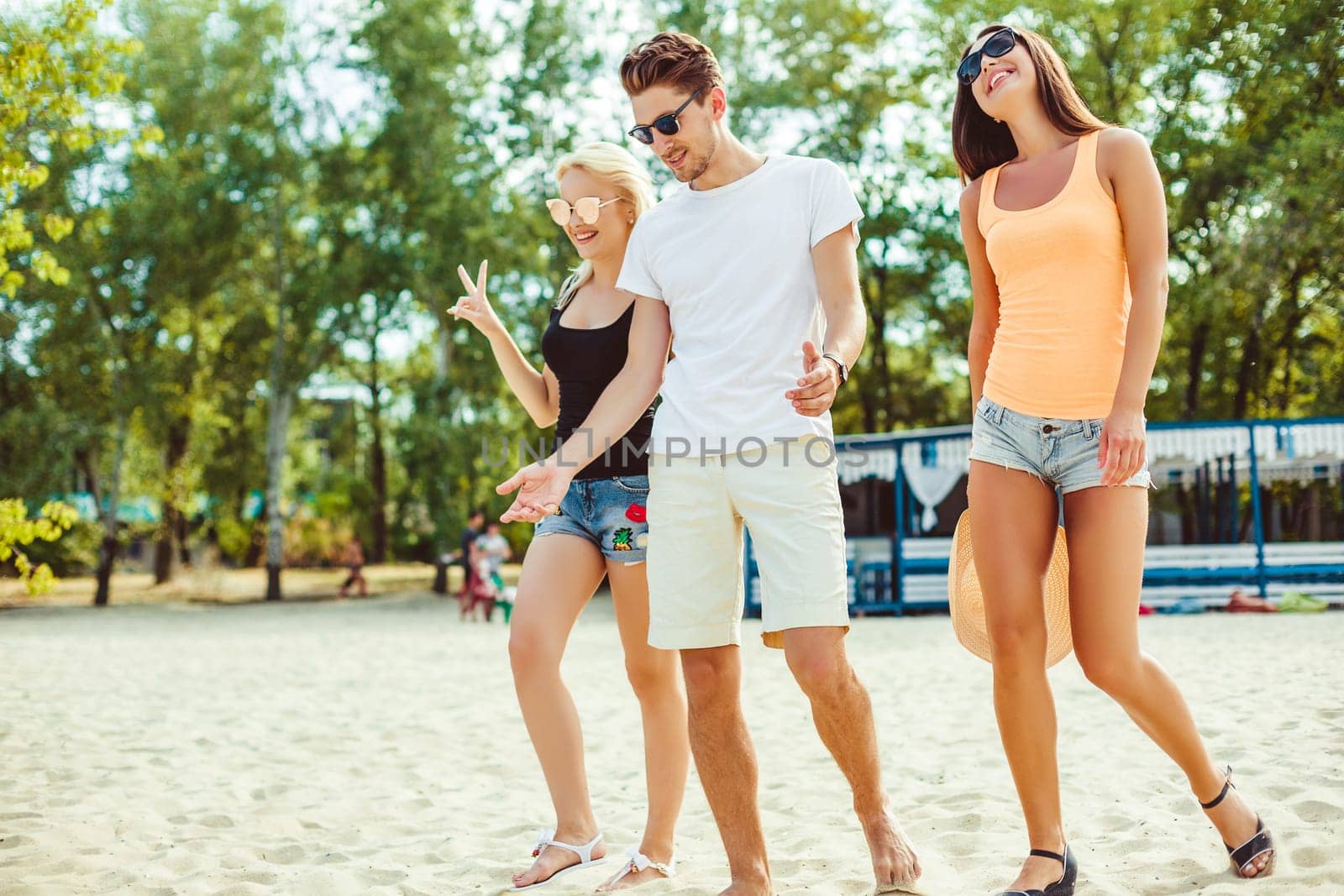 Young funny guys in sunglasses on the beach. Friends together. Summer bar is on background.