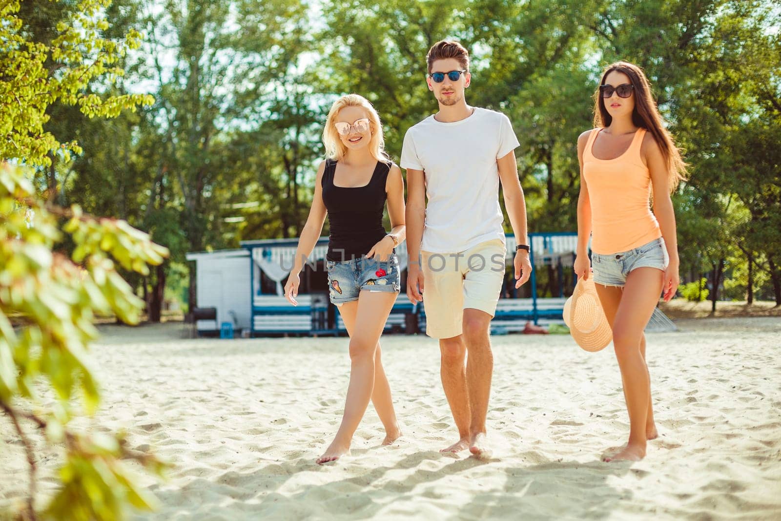 Young funny guys in sunglasses on the beach. Friends together. Summer bar is on background.