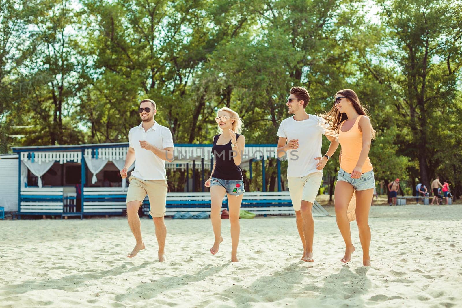 Young funny guys in sunglasses on the beach. Friends together. Summer bar is on background.