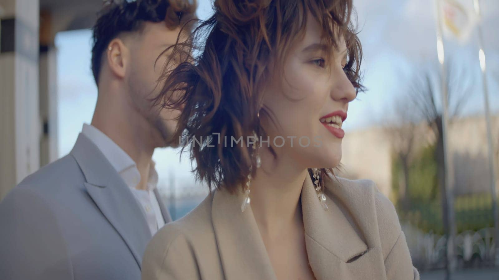 Stylish and happy couple in suits. Action. Beautiful couple is laughing on city street. Couple in stylish outfits smiling happily.