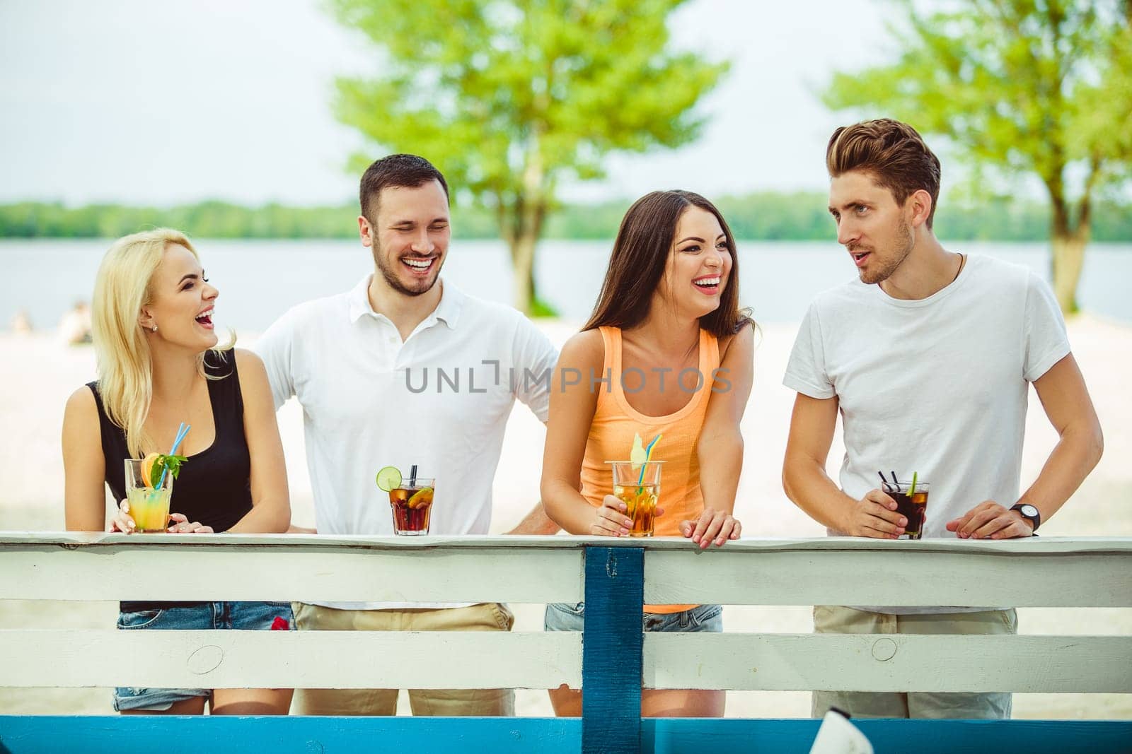 Friends having fun at the bar outdoors, drinking cocktails. by nazarovsergey