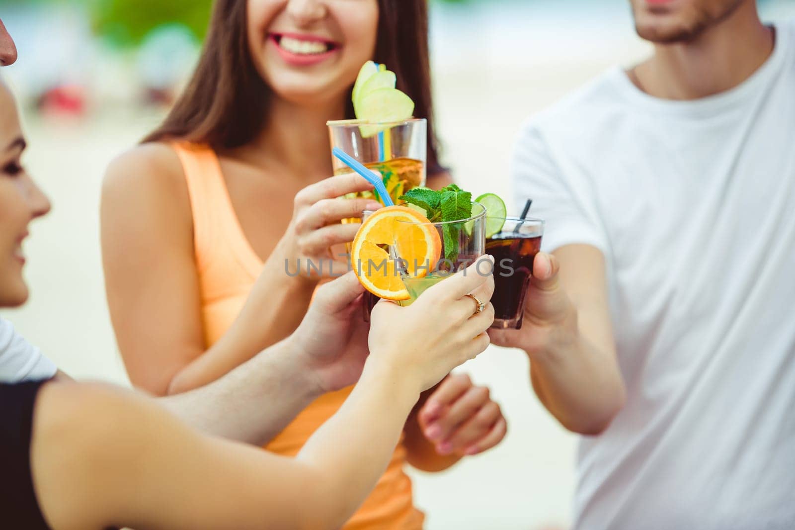 Friends having fun at the bar outdoors, drinking cocktails. by nazarovsergey