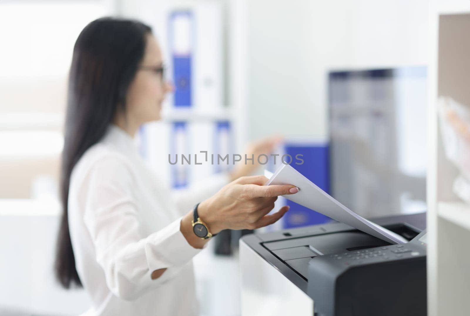 Young woman pulling paper out of printer closeup. Replacement of cartridges and repair of office equipment concept