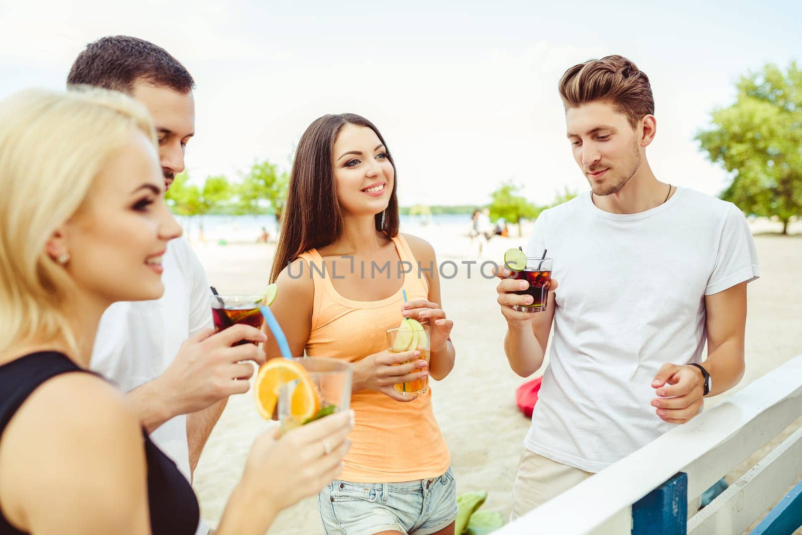 Friends having fun at the bar outdoors, drinking cocktails. by nazarovsergey