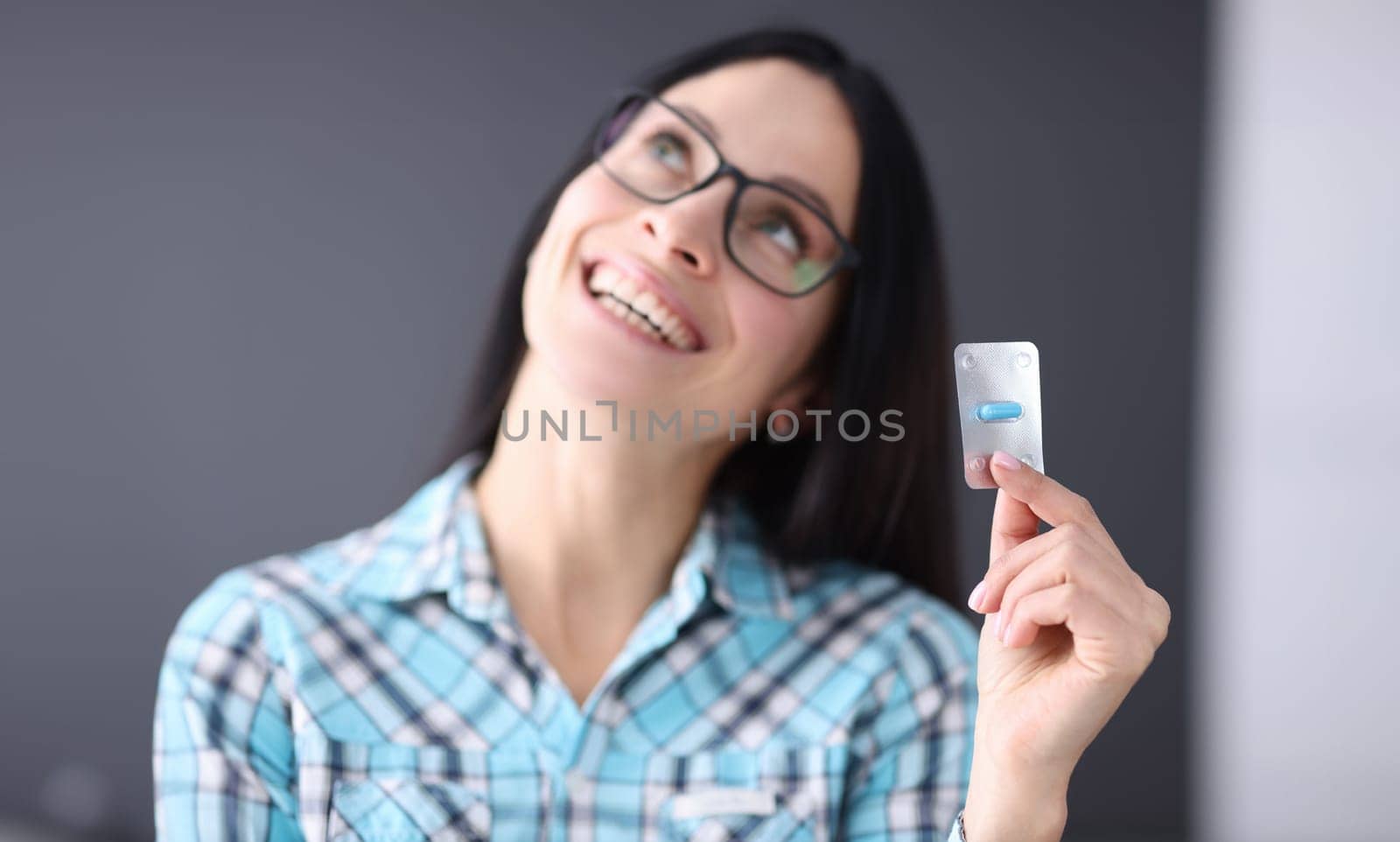 Contented woman holding blister with one capsule in her hands. Emergency hormonal contraception concept