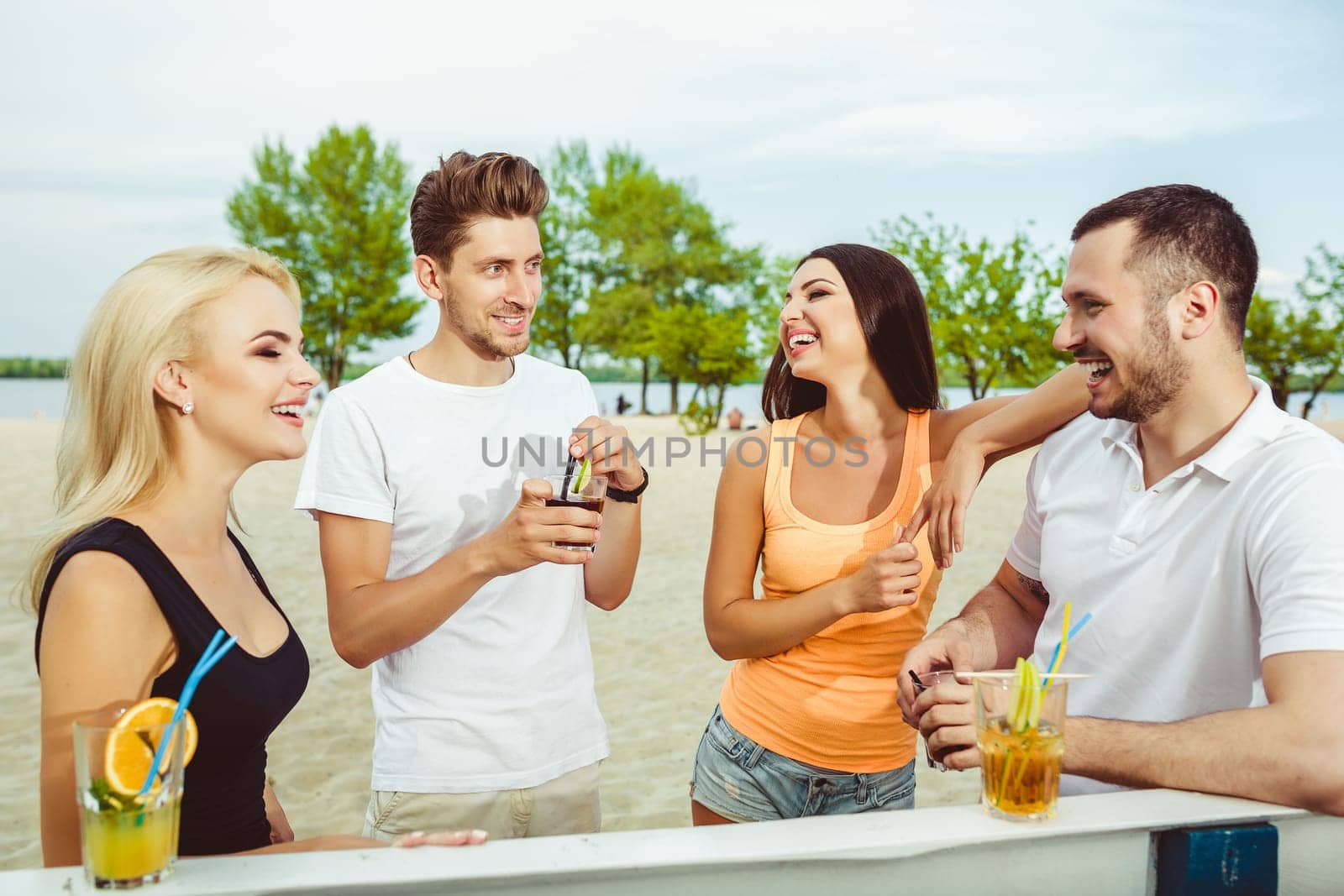 Friends having fun at the bar outdoors, drinking cocktails. by nazarovsergey