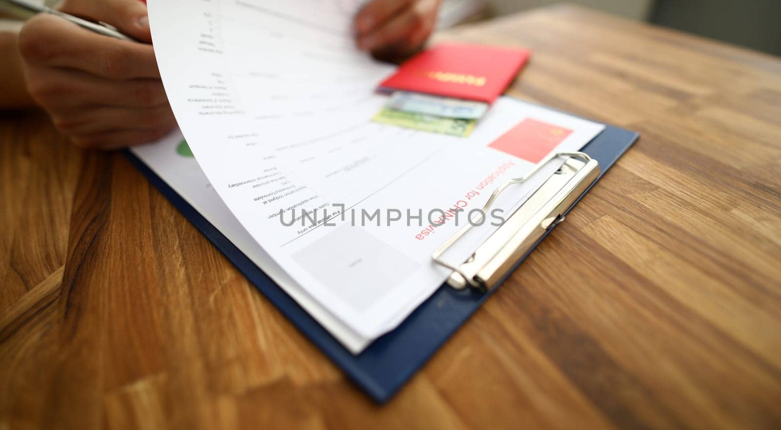 Male hand hold silver pen with passport. Filling China apllication form concept