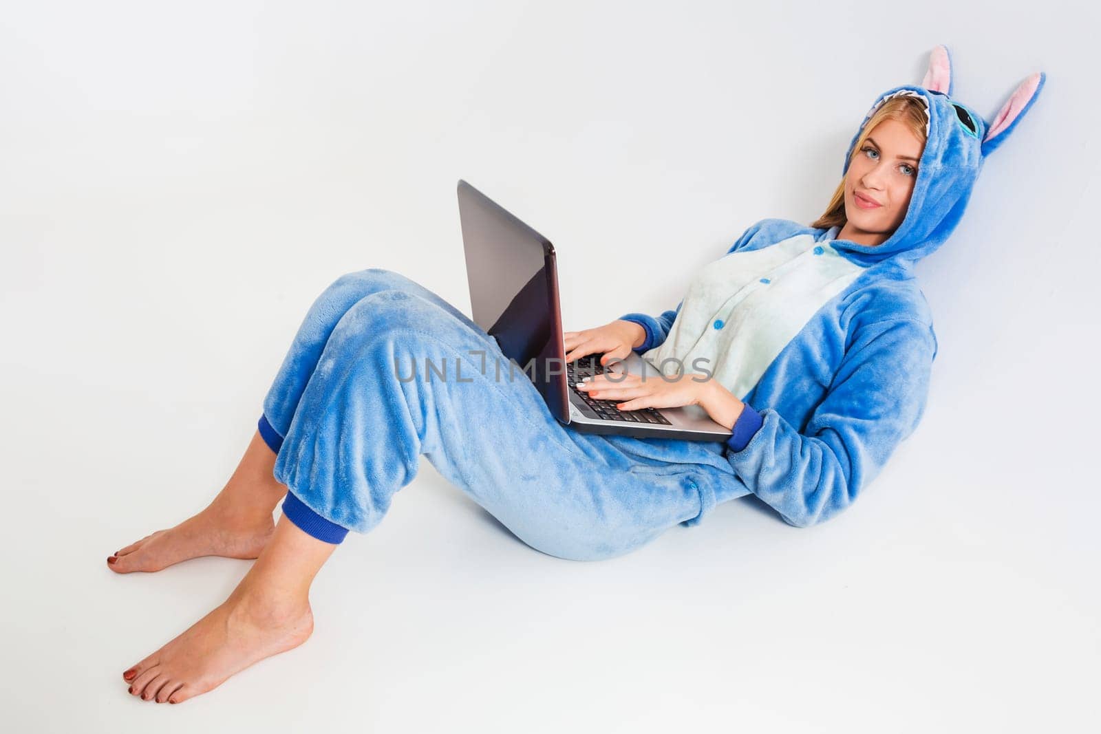 girl in pajamas with a laptop lying on the floor. studying or doing online shopping. work from home. Satisfied and smiling