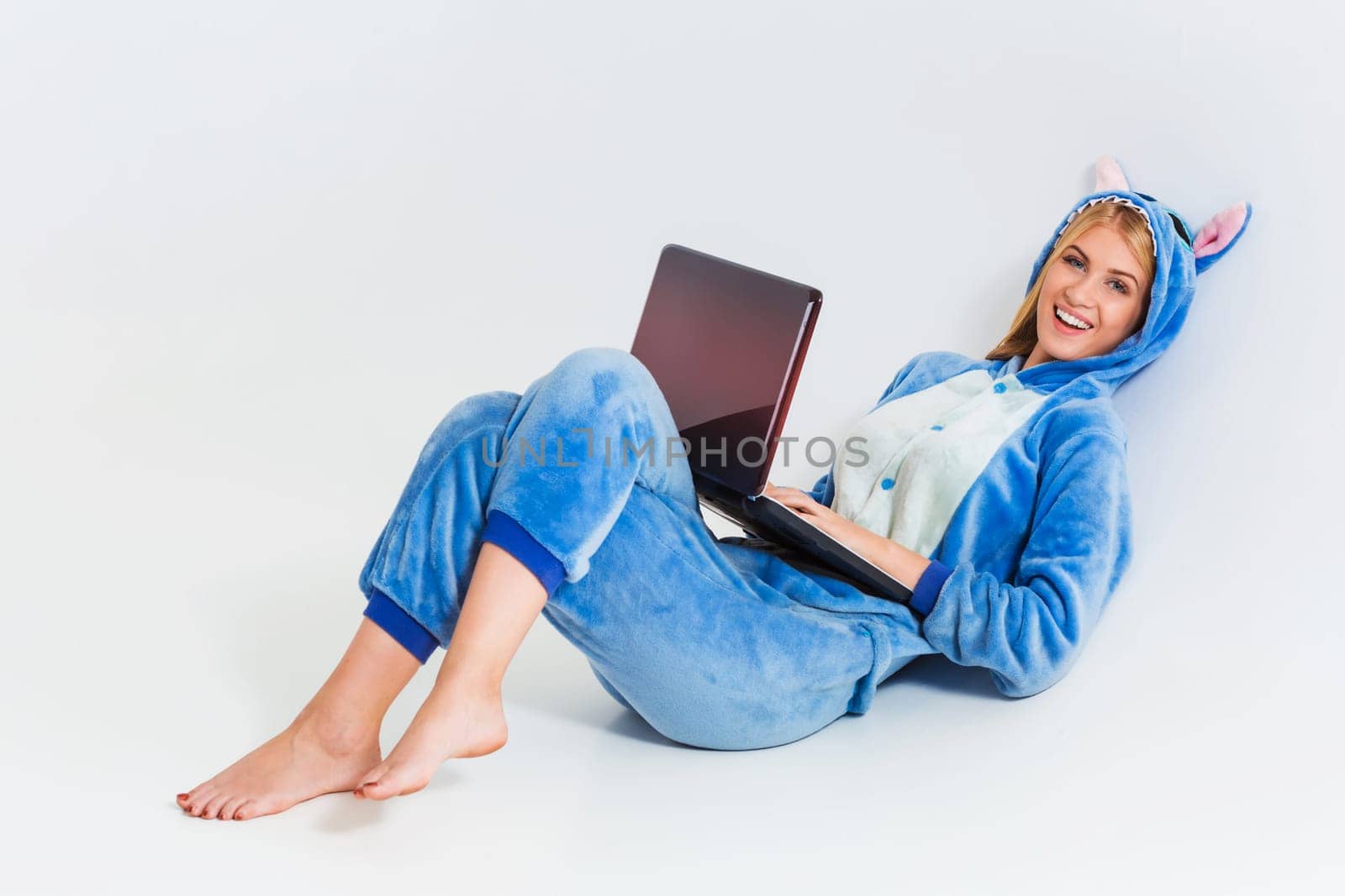 girl in pajamas with a laptop lying on the floor. studying or doing online shopping. work from home. Satisfied and smiling