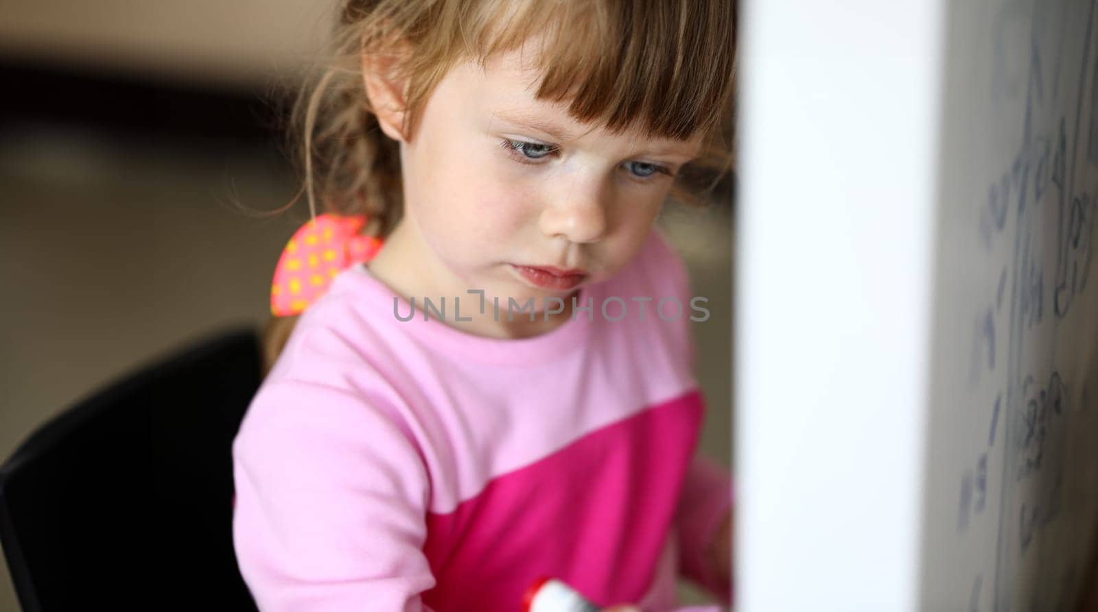 Portrait of smart beautiful kid looking at something with great concentration and attention. Trendy child wearing fashionable sweater. Creative childhood concept