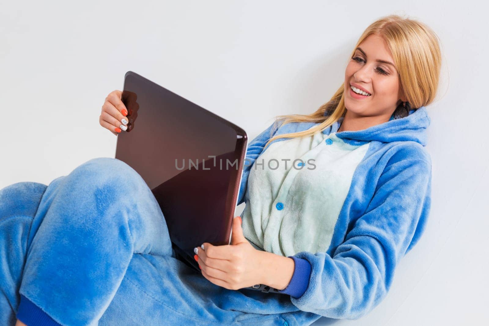 girl in pajamas with a laptop lying on the floor. studying or doing online shopping. work from home. Satisfied and smiling