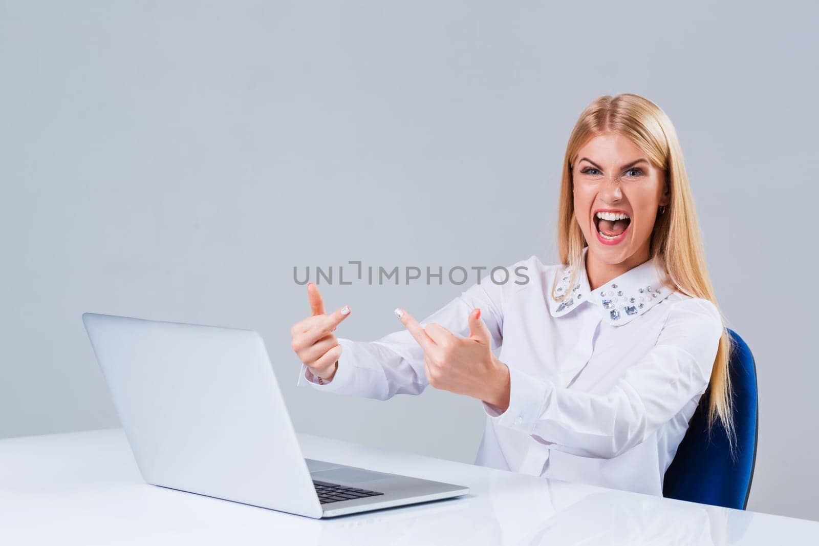 Young businesswoman working at laptop computer. dissatisfied showing middle finger