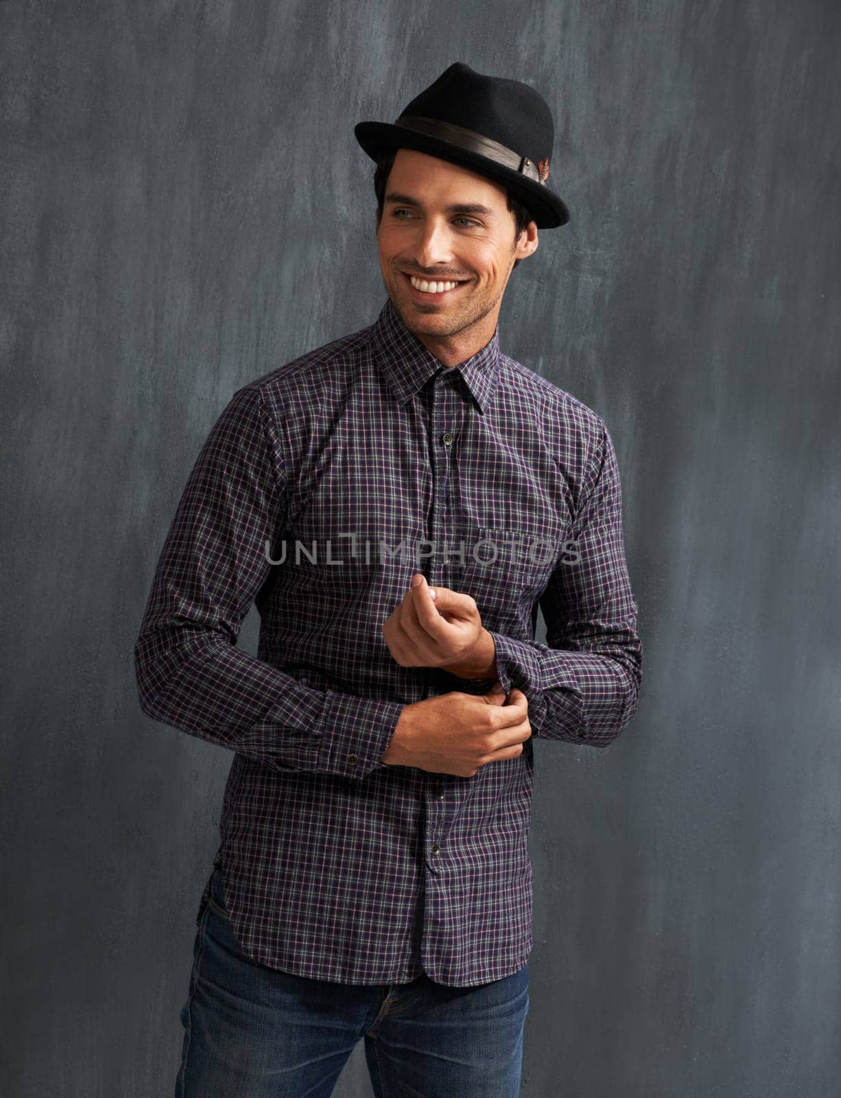 Fashion, happy and man on gray background with confidence in trendy style, clothes and casual outfit. Smile, handsome and face of person on texture wall with accessory, pride and positive attitude by YuriArcurs
