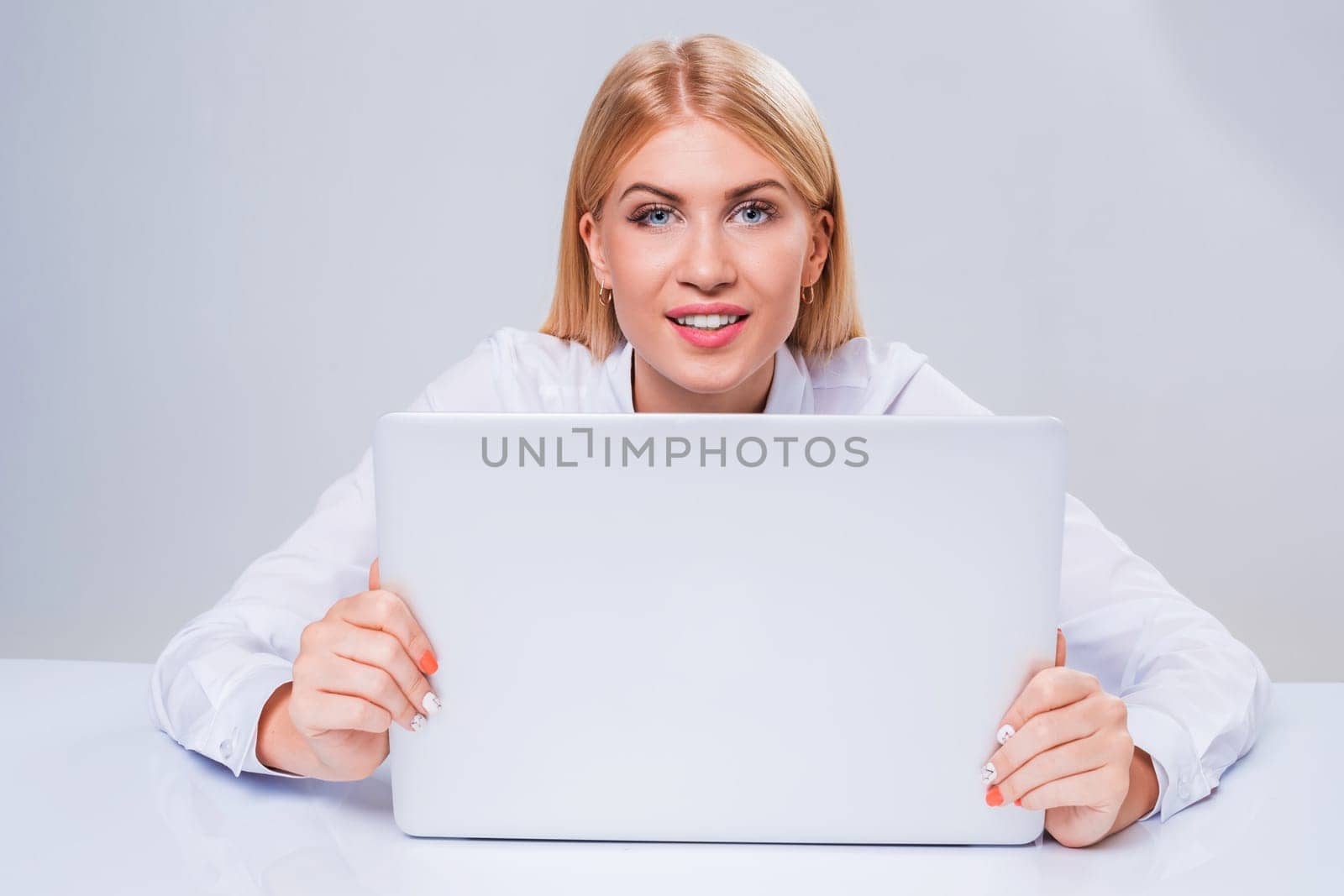 Young businesswoman working at laptop computer. hiding behind the monitor contented happy girl