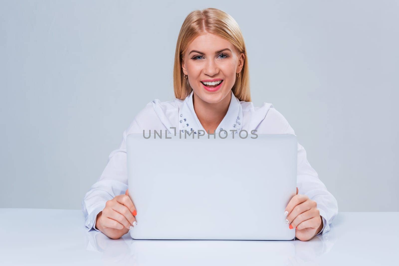 Young businesswoman working at laptop computer. hiding behind the monitor contented happy girl