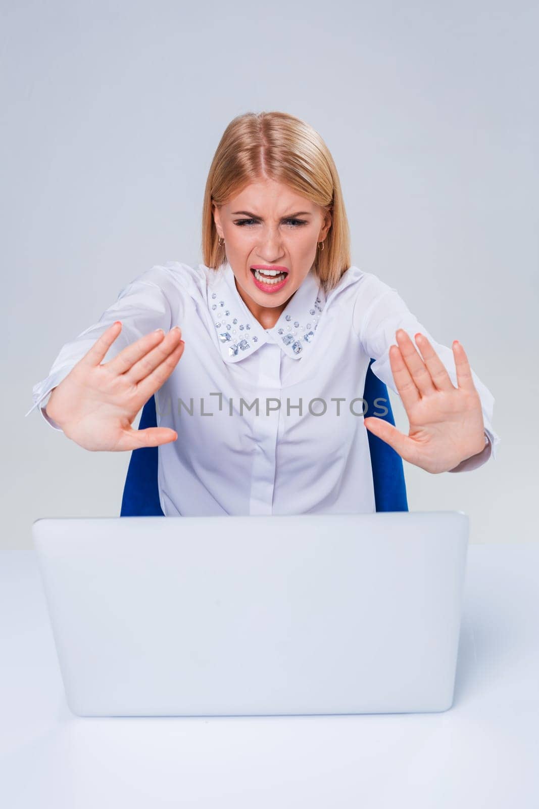 Young businesswoman working at laptop computer. hiding behind the monitor. frustrated, spiteful woman in shock