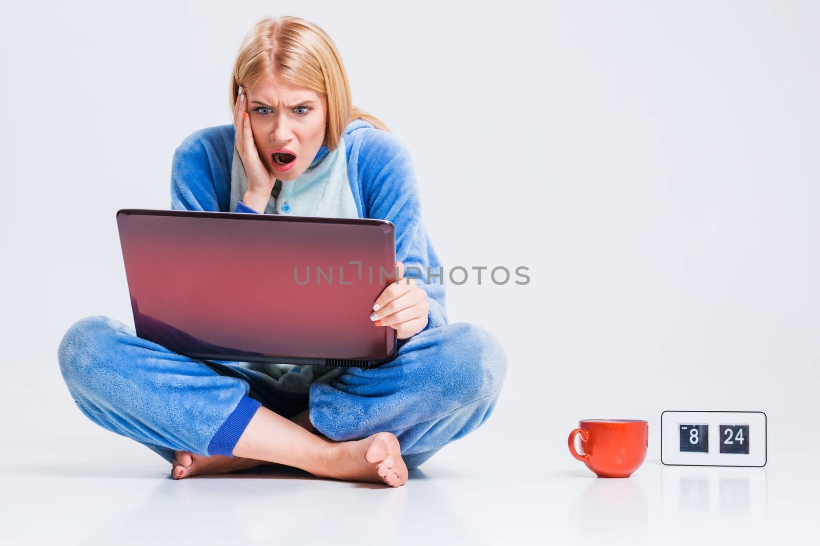 girl in pajamas with a laptop lying on the floor. studying or doing online shopping. work from home. Surprised and crazy