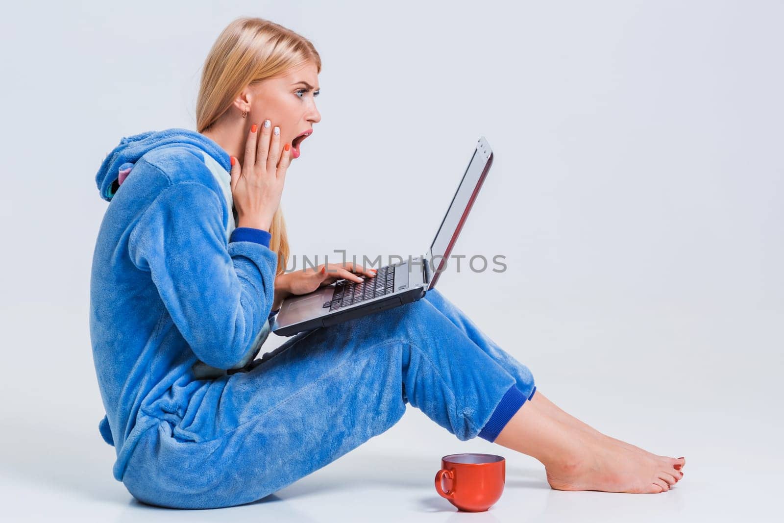 girl in pajamas with a laptop lying on the floor. studying or doing online shopping. work from home. Surprised and crazy