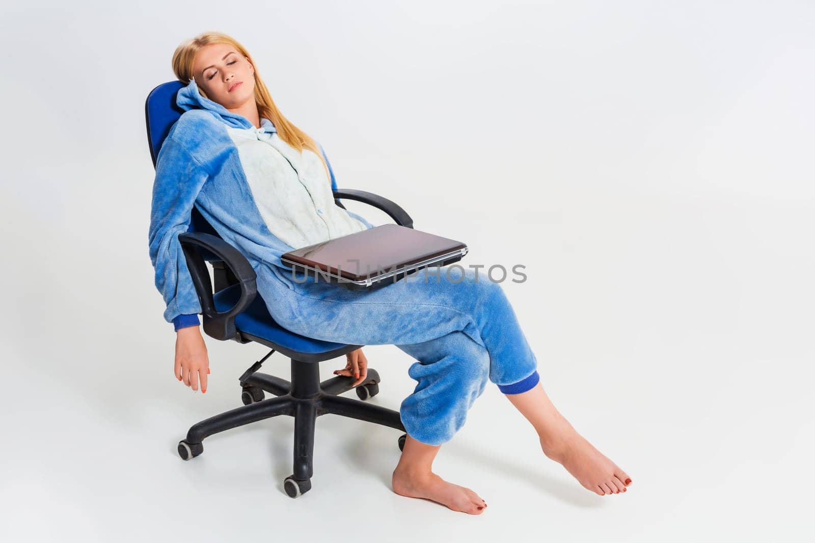girl in pajamas with a laptop. studying or doing online shopping. work from home. tired of sleeping in a chair
