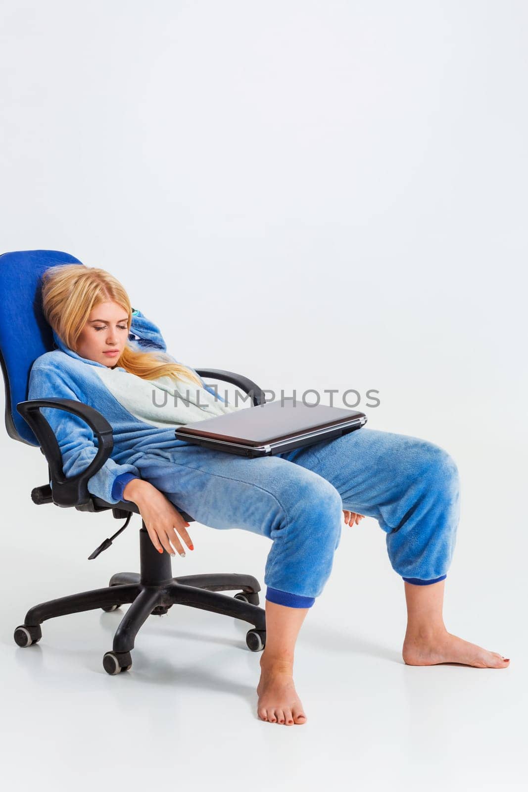 girl in pajamas with a laptop. studying or doing online shopping. work from home. tired of sleeping in a chair