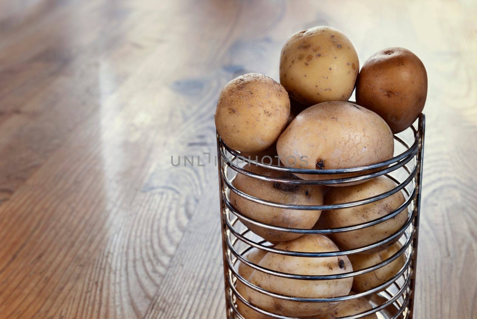 Whole yellow potatoes in bowl on wooden table , uncooked and unpeeled vegetable