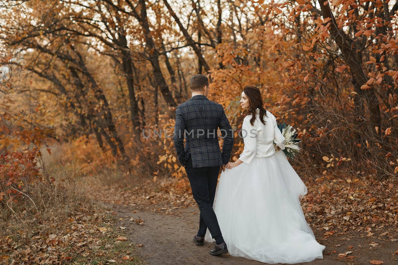 bride and groom walking outside in autumn