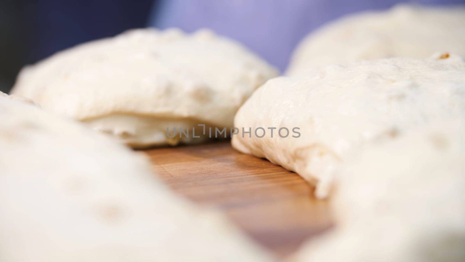 Close up view for raw pieces of pastry lying on the wooden board on the table. Traditional delicious pastry pieces with raisins ready for baking.