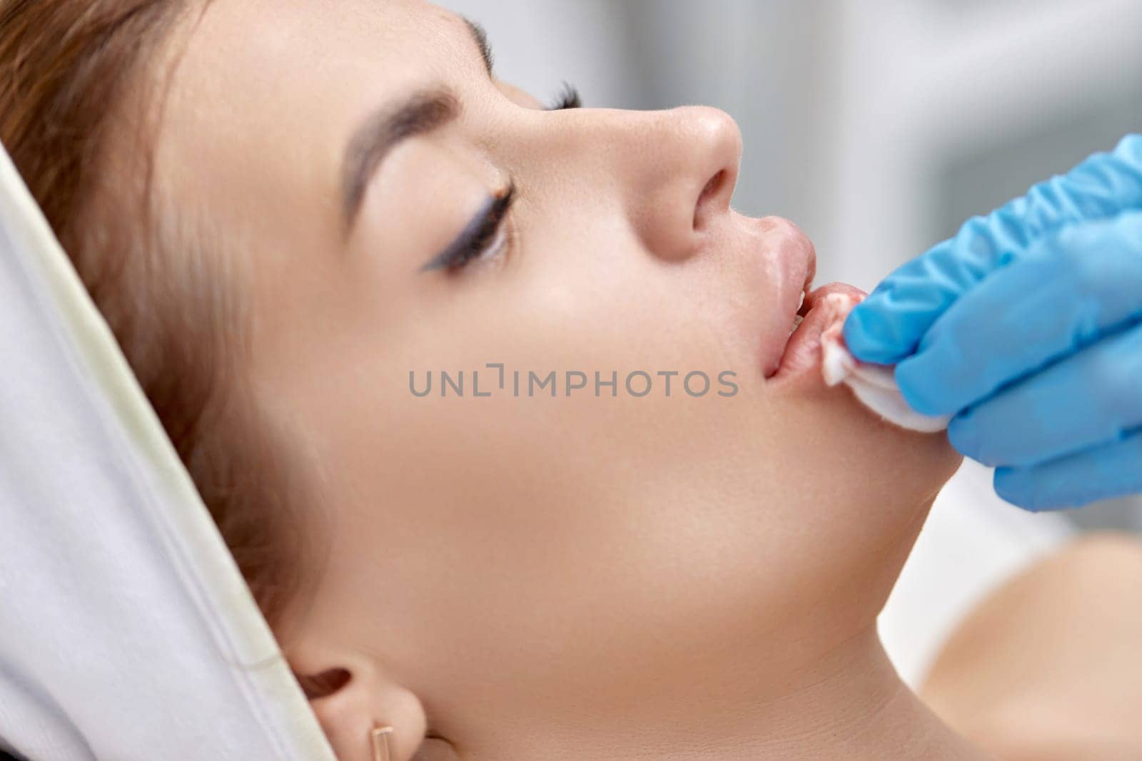 woman receives cosmetic injection in lips. beauty salon. by erstudio