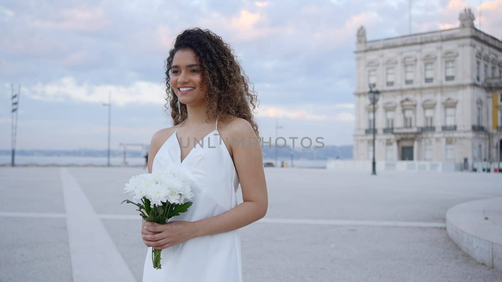 A lovely lady with a bouquet of flowers. Action. A woman walking around the city in a light short dress and smiling. by Mediawhalestock