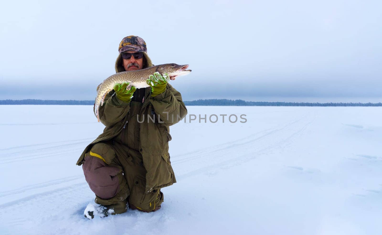 Man Holding a Fish in the Snow. Winter fishing, adventure. Banner, copy space