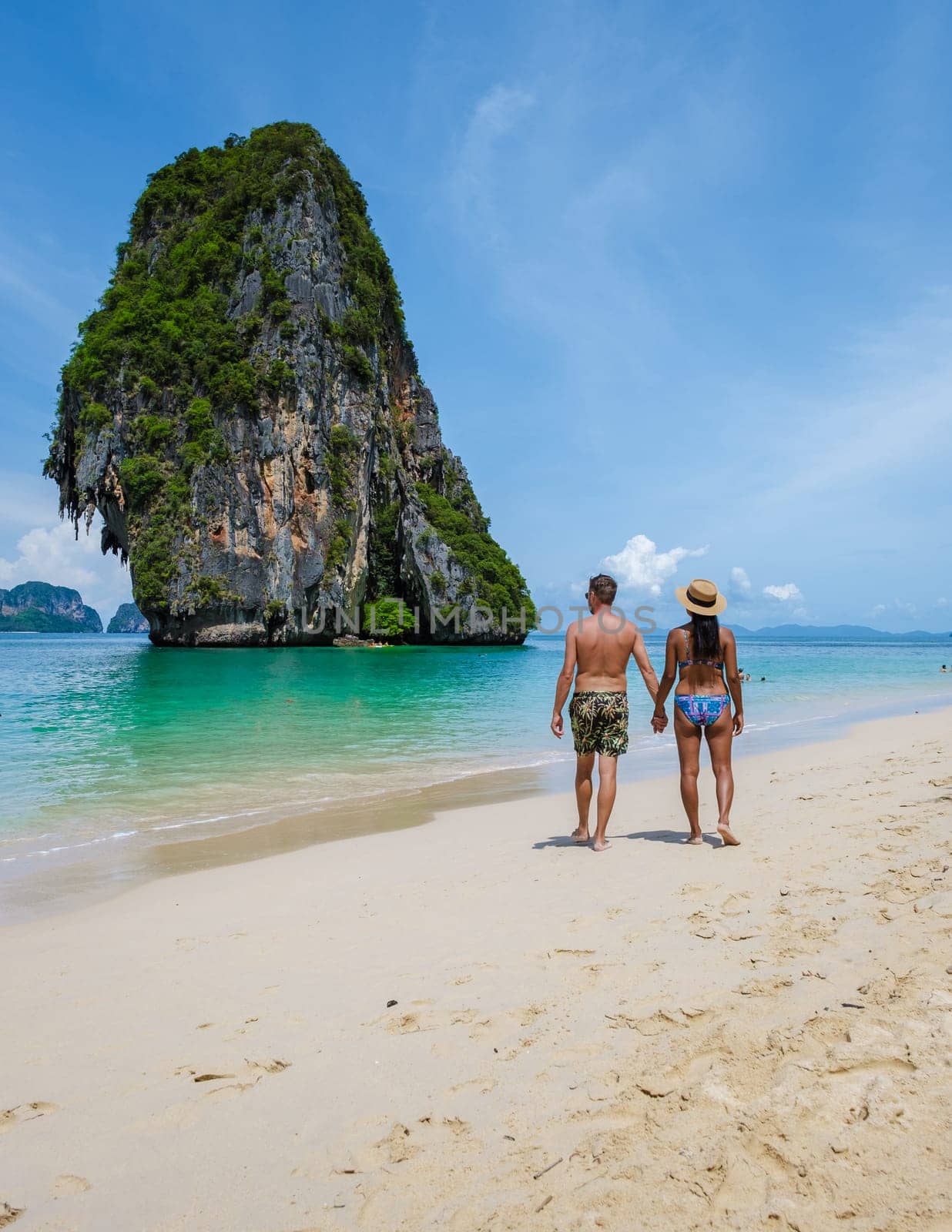 Railay Beach Krabi Thailand, the tropical beach of Railay Krabi, a couple of men and women on the beach, Panoramic view of idyllic Railay Beach in Thailand on a sunny day with a blue sky