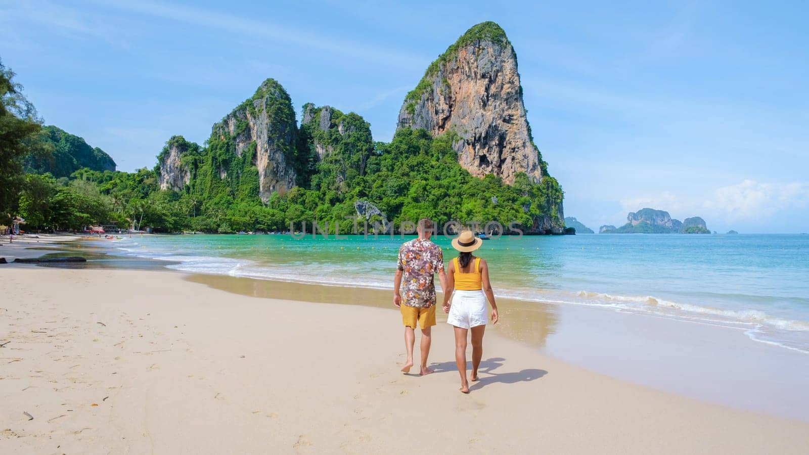 Railay Beach Krabi Thailand, the tropical beach of Railay Krabi, a couple of men and women on the beach, Panoramic view of idyllic Railay Beach in Thailand on a sunny day with a blue sky