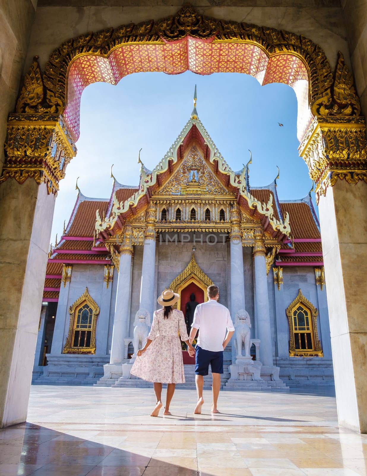 Wat Benchamabophit temple in Bangkok Thailand, The Marble temple in Bangkok. Asian woman with a hat and European men visiting a temple, a couple on a city trip in Bangkok