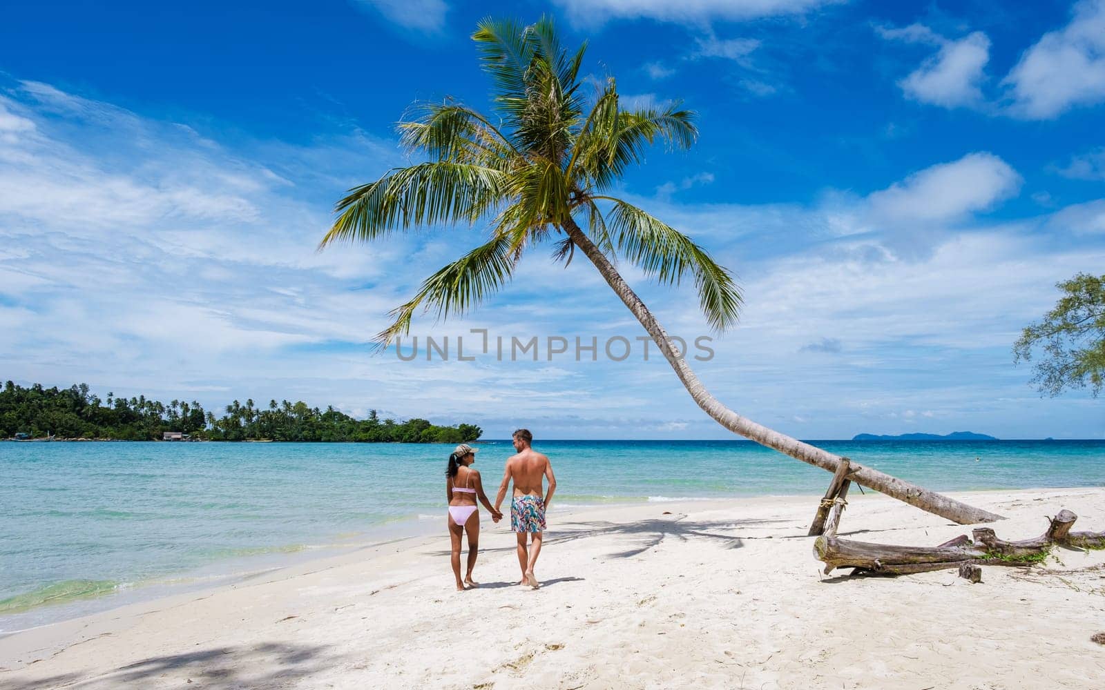 Tropical Island Koh Kood or Koh Kut Thailand. Couple men and women on vacation in Thailand walking at the beach with a hanging palm tree, holiday concept Island hopping in Eastern Thailand Trang