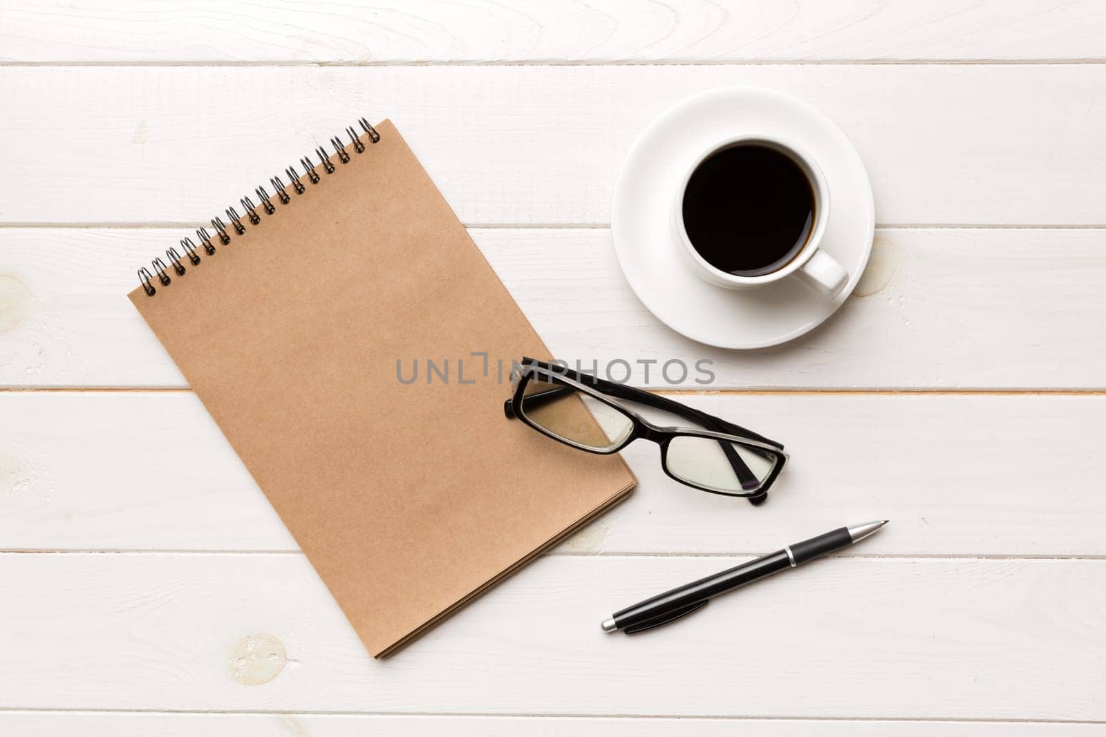 Modern office desk table with notebook and other supplies with cup of coffee. Blank notebook page for you design. Top view, flat lay by Snegok1967